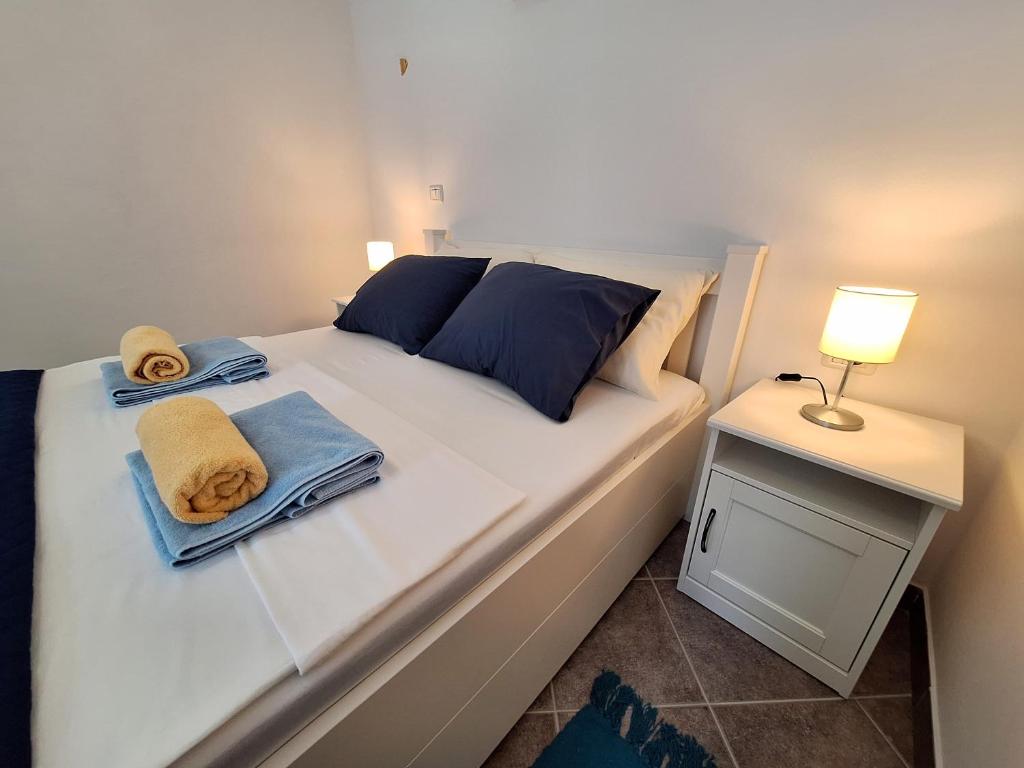 ein weißes Bett mit Handtüchern und einer Lampe auf dem Tisch in der Unterkunft Apartment Libra in Piran