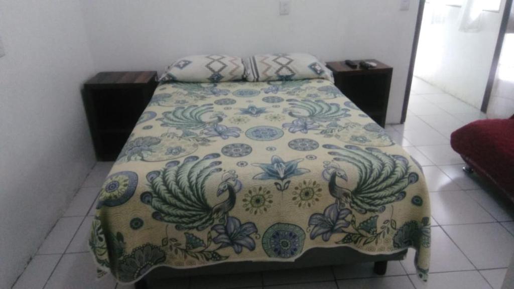 a bedroom with a bed with a flowered blanket at Departamento CUARTITO MODESTO DEL PRECIOSO in Martínez de La Torre