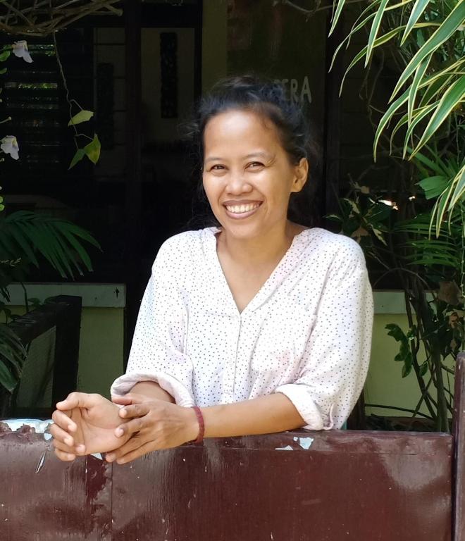a woman is smiling while leaning against a fence at Homestay Galpera Papua in Jayapura