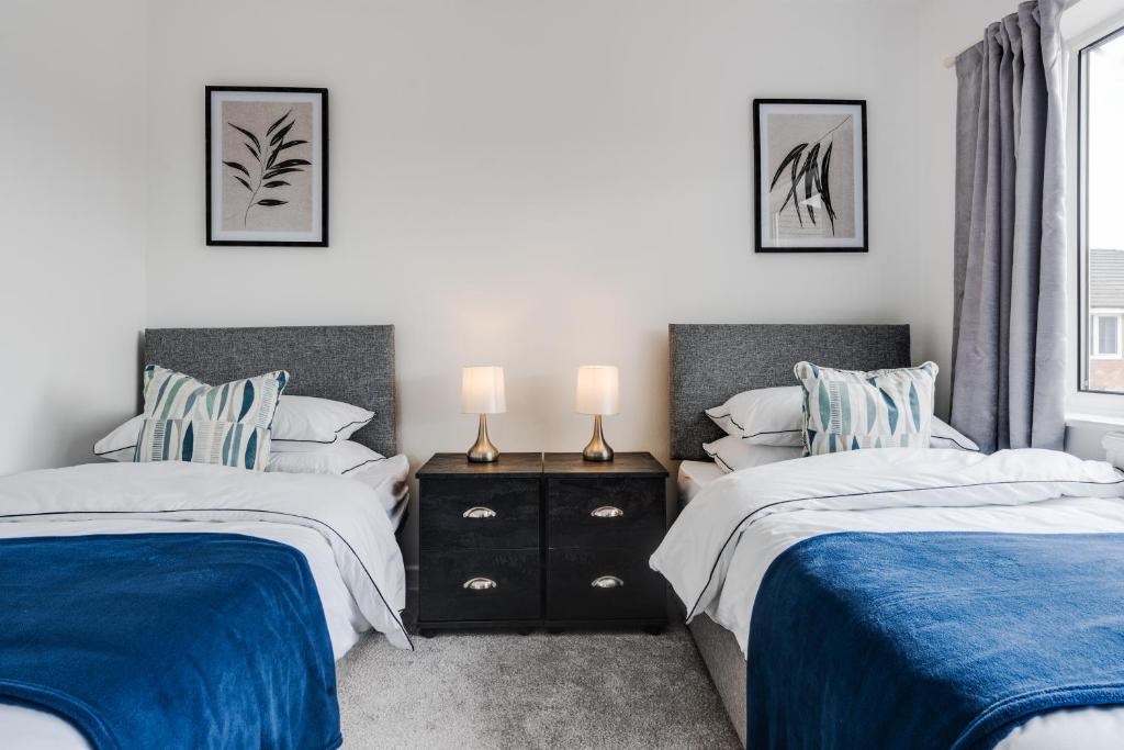 a bedroom with two beds with blue and white sheets at The Serenity, Three bedroom house, Preston in Walton le Dale