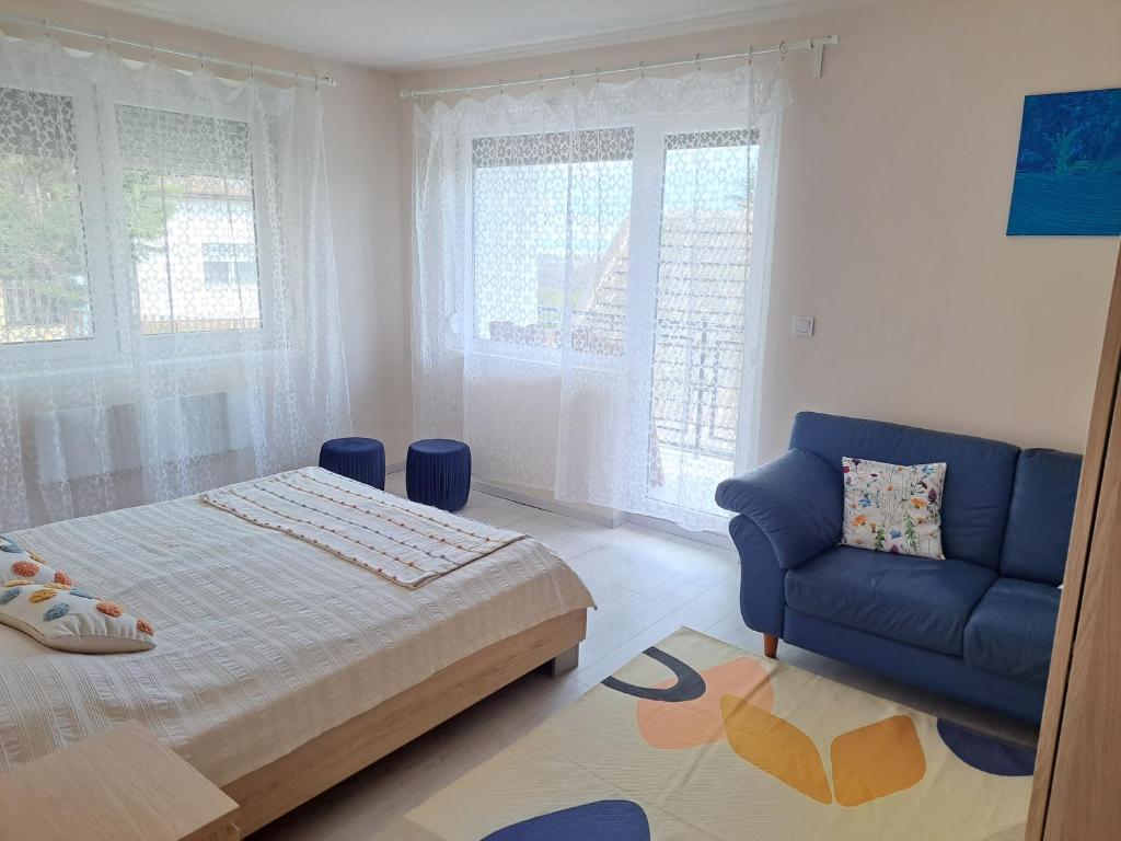 um quarto com uma cama e um sofá azul em Corner Vendégház - Zánka em Zánka