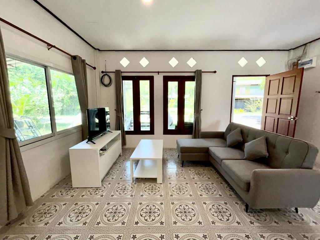 a living room with a couch and a tv at Modern Sunset Sea House Lam Sai in Ko Yao Noi