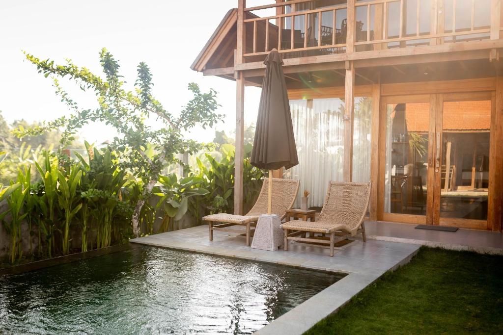 a house with a pool and two chairs and an umbrella at Bruann residence villa 2 Seseh Perenenan amazing views in Munggu