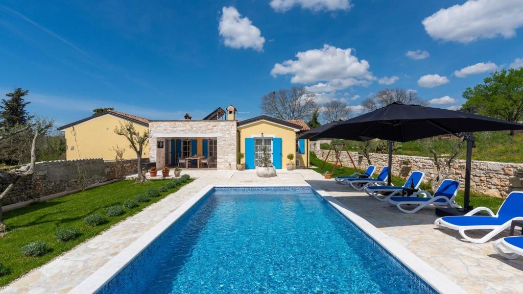una piscina con sedie e ombrelloni accanto a una casa di Villa Iria Bella a Marčana