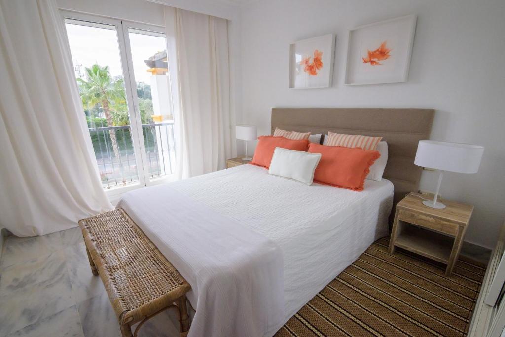 een slaapkamer met een bed met oranje kussens en een raam bij La Dama de Noche - Marbella Puerto Banus in Marbella