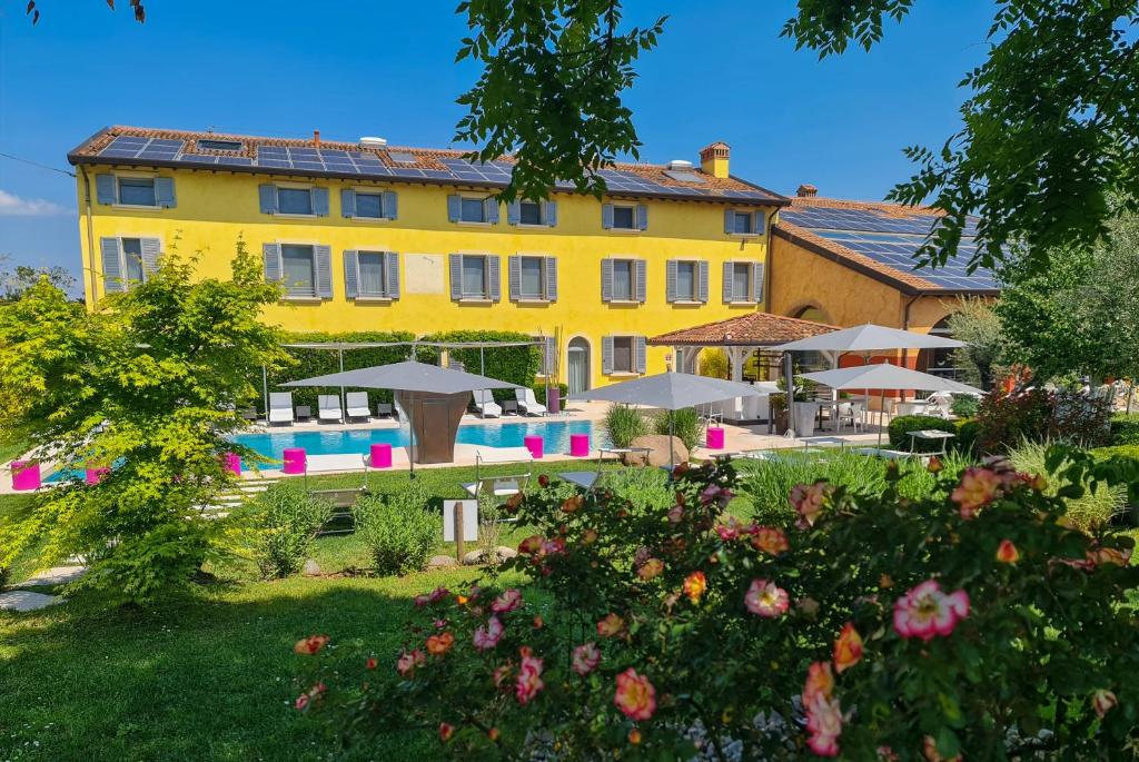a yellow building with a pool and umbrellas at Hotel Corte Del Paggio in Valeggio sul Mincio