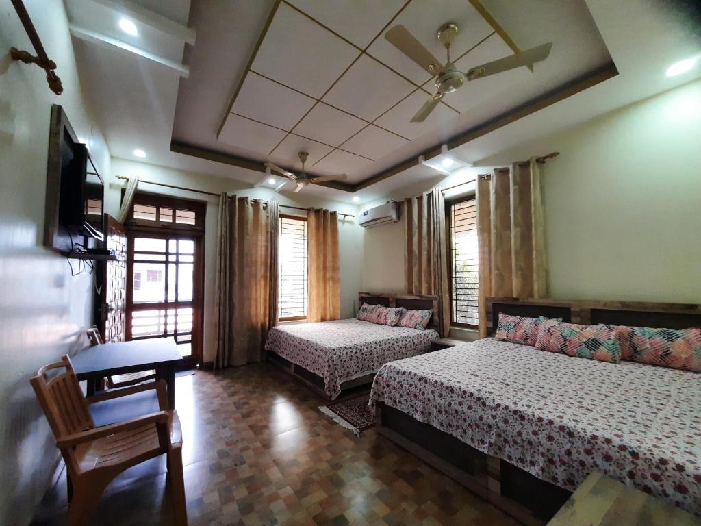 Cette chambre comprend deux lits, un canapé et une table. dans l'établissement Bora's Homestay, à Haldwani