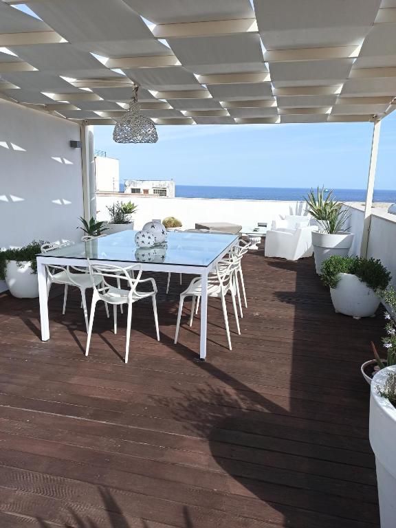 un patio con tavolo, sedie e vista sull'oceano di Attico San Domenico a Trapani