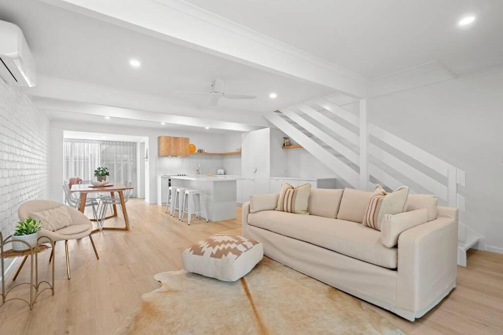 a living room with a white couch and a kitchen at Vibes At Five Noosa in Noosaville