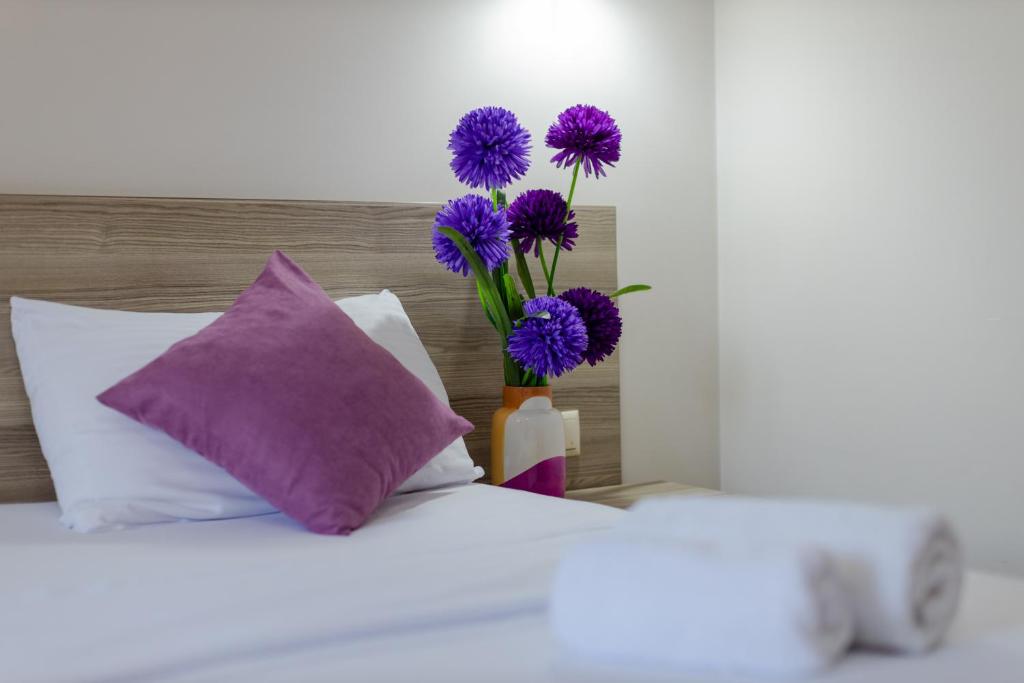 a vase with purple flowers sitting on top of a bed at Daisi Sunset Hotel in Batumi