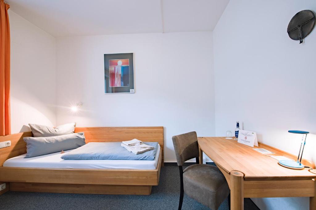 Schlafzimmer mit einem Bett, einem Schreibtisch und einem Tisch in der Unterkunft Hotel der Akademie C. Pirckheimer Haus in Nürnberg
