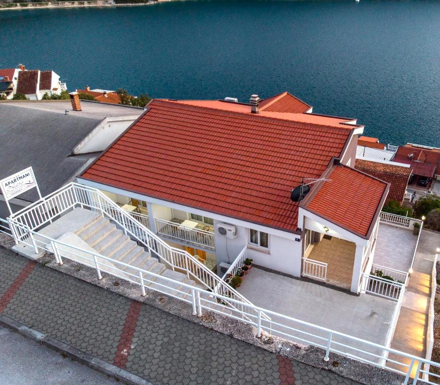 a house with a red roof next to the water at Apartments Njavro Neum in Neum