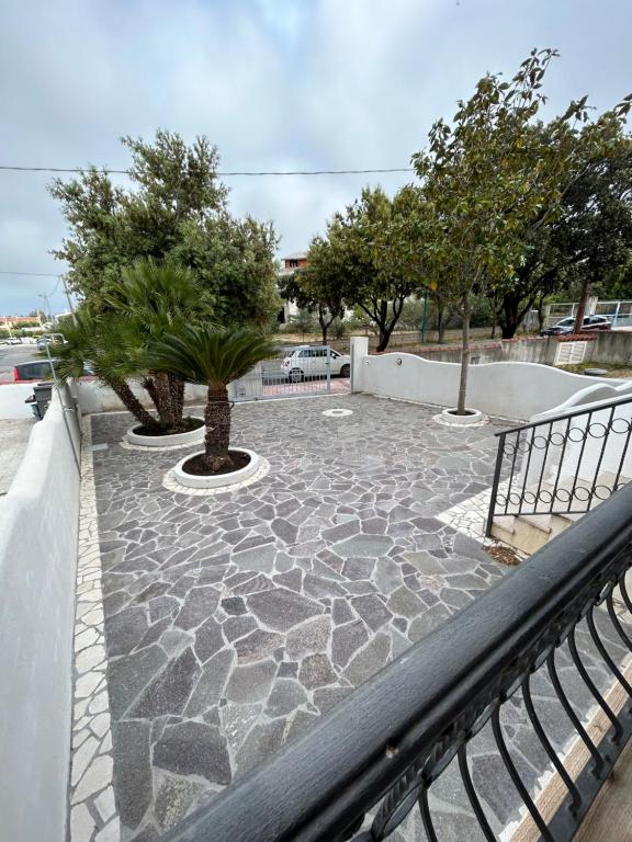 een stenen terras met twee bomen en een hek bij Casa Mario e Rosa in Orosei