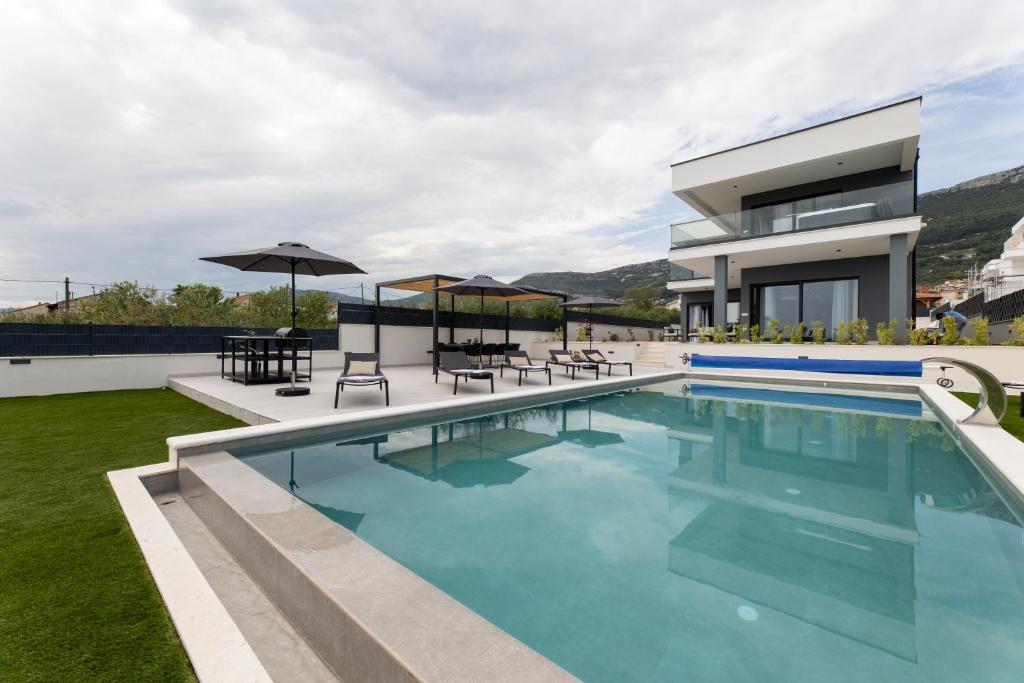 a villa with a swimming pool and a house at Villa Duje in Kastel Stari