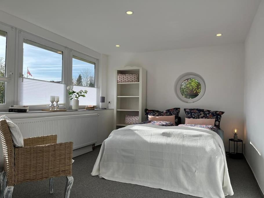 a white bedroom with a bed and a window at Idyllisches Ferienhäuschen Rendsburg in Rendsburg