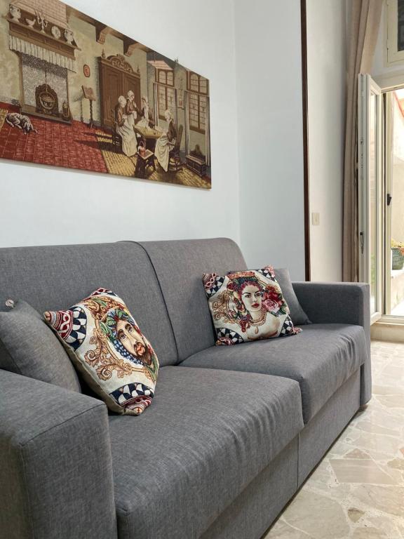 ein graues Sofa mit zwei Kissen im Wohnzimmer in der Unterkunft November House Cefalù in Cefalú