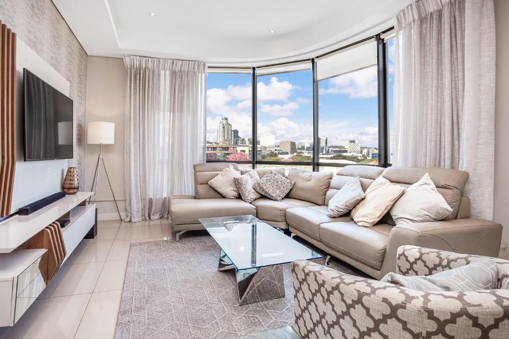 een woonkamer met een bank en een groot raam bij Sandton Skye Serviced Apartments in Johannesburg