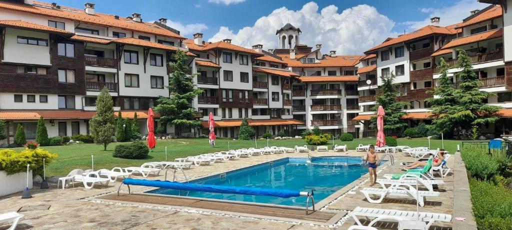 a resort with a pool and chairs and buildings at Katy's studio in Bansko