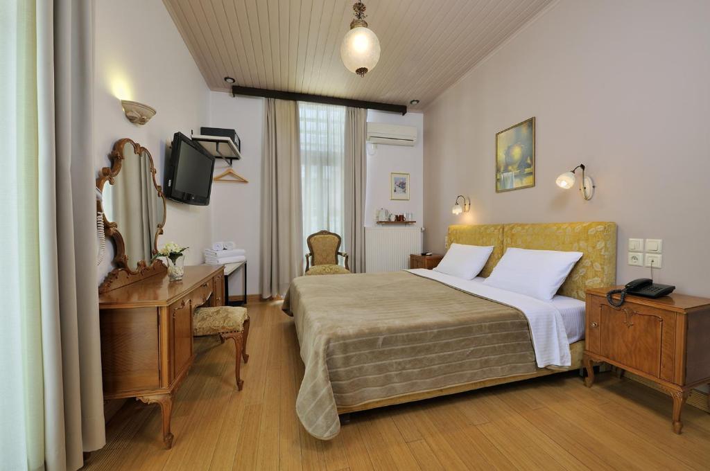 a bedroom with a bed and a desk and a mirror at Dryades & Orion Hotel in Athens