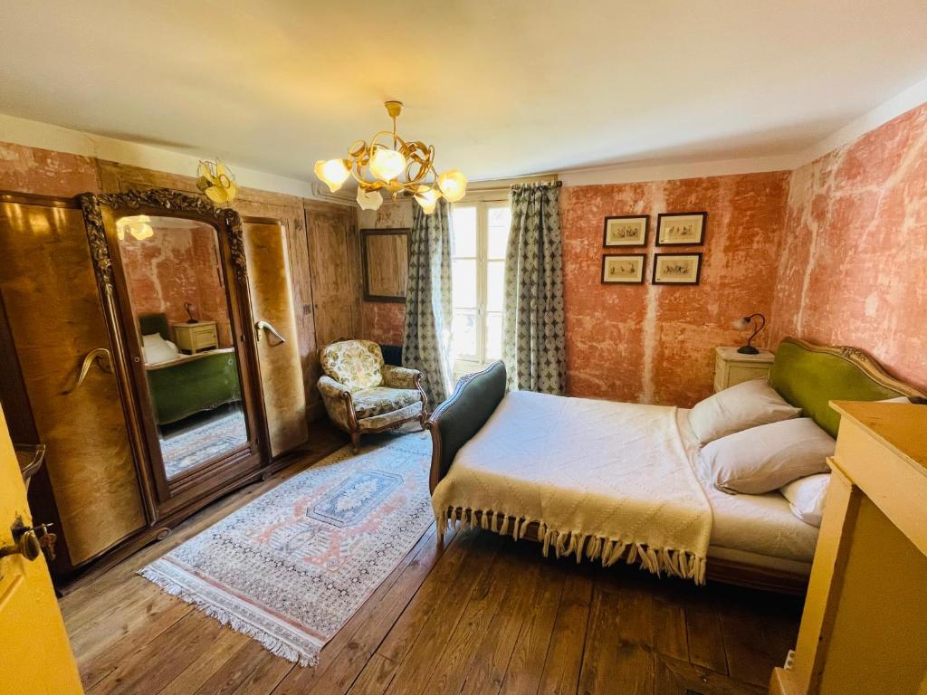ein Schlafzimmer mit einem Bett, einem Spiegel und einem Stuhl in der Unterkunft Epicerie Vieille du Puy en Velay in Le Puy en Velay