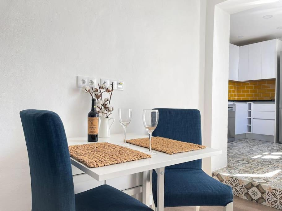 a dining room table with two chairs and a table with wine glasses at Casa da Oliveira in Évora