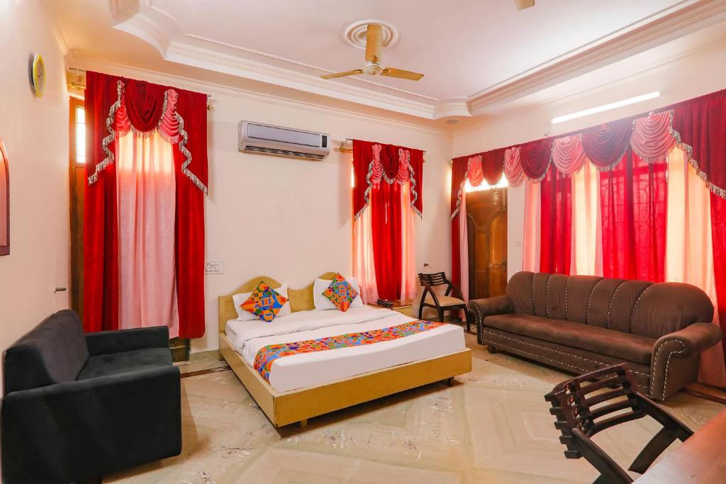 a bedroom with a bed and a couch and red curtains at FabHotel Raka Inn in Allahābād