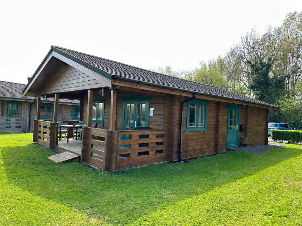 a small wooden cabin with a table in a yard at Lake Pochard, Oak Lodge in South Cerney