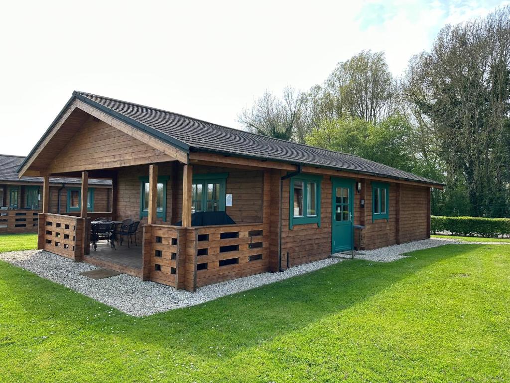 a log cabin with a porch and a green door at Kingfisher Lodge, Lake Pochard in South Cerney