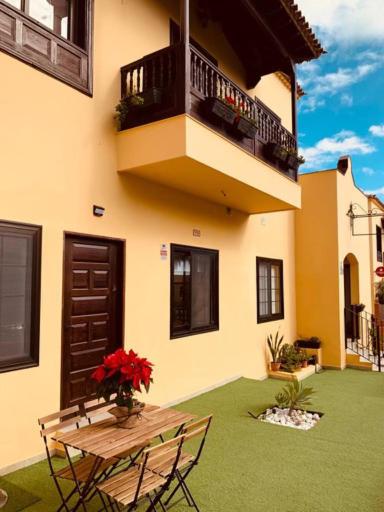 un edificio con una mesa y un balcón con un jarrón de flores en LAS MESAS HOUSE Ocean Escape, en San Miguel de Abona