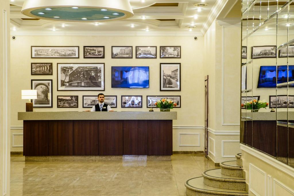 カルーガにあるHistorical Hotel Kalugaのホテルロビーのカウンターに立つ男