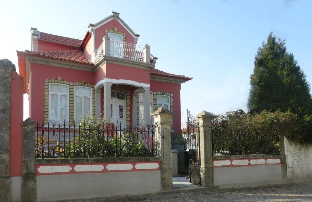 uma casa cor-de-rosa com uma vedação à frente. em Casa do Sino de Aveiro em Estarreja