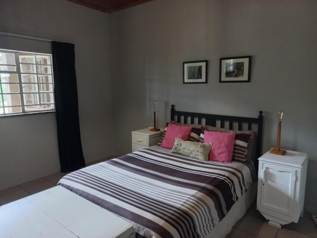 a bedroom with a large bed with pink pillows at Orange Elephant Backpackers in Addo