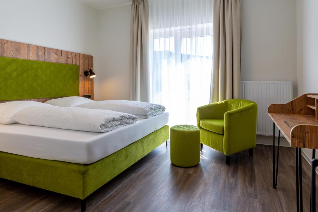 a bedroom with a bed and a green chair at Hotel Fuchsbau Jüterbog in Jüterbog