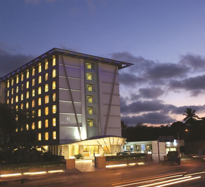 a lit up building at night with a street at Mirage Hotel in Mumbai