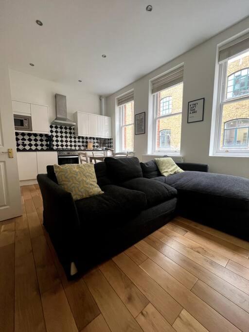 een woonkamer met een zwarte bank en een keuken bij 1-Bed Flat in Historic Camden in Londen