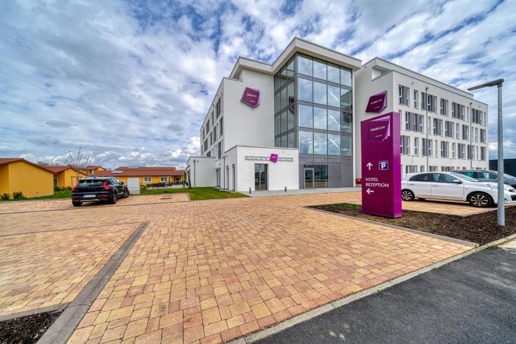 a large building with a purple sign in a parking lot at FourSide Hotel Ringsheim in Ringsheim