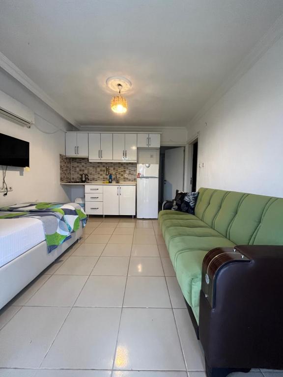 Koparan Apart Hotel في أكياكا: غرفة معيشة مع أريكة خضراء ومطبخ
