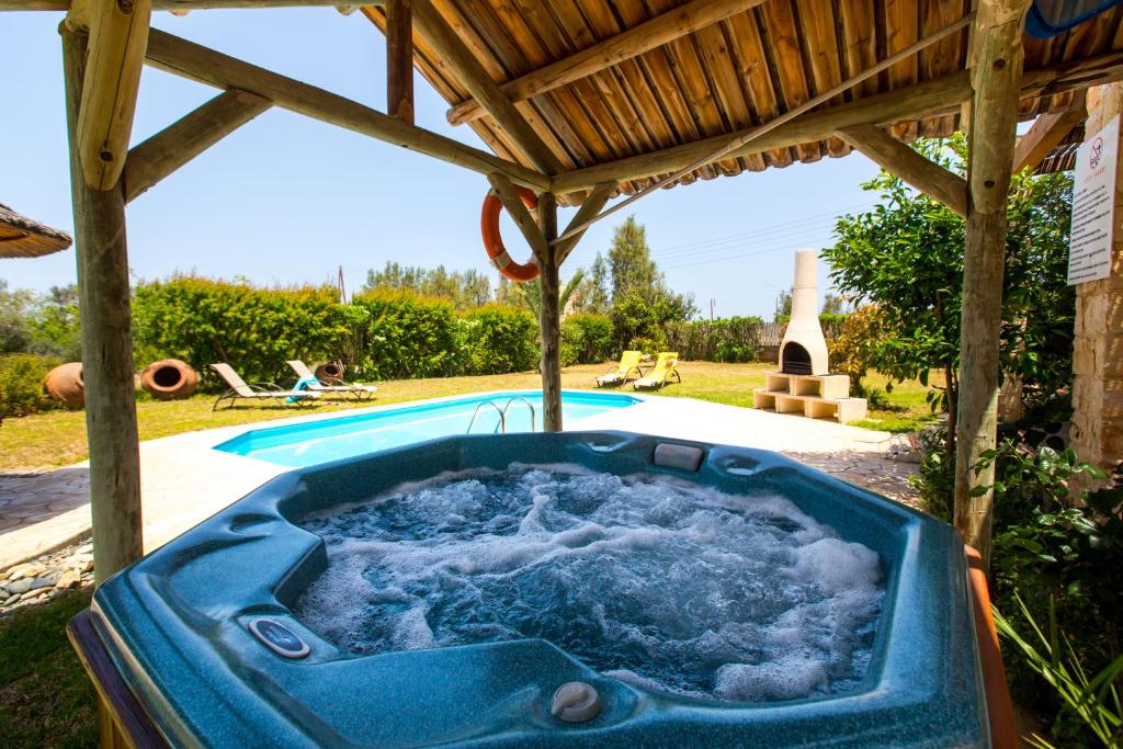 Villa Pomos Med. في بوموس: حوض استحمام ساخن تحت pergola بجوار حمام سباحة