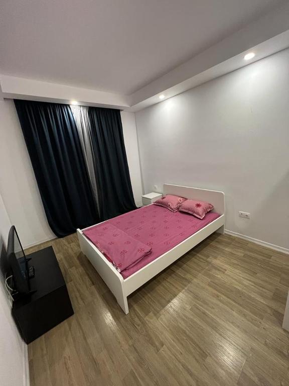 a bedroom with a large bed with pink sheets at Cosmopolis Single Bedroom Apartment 204 in Creţuleasca
