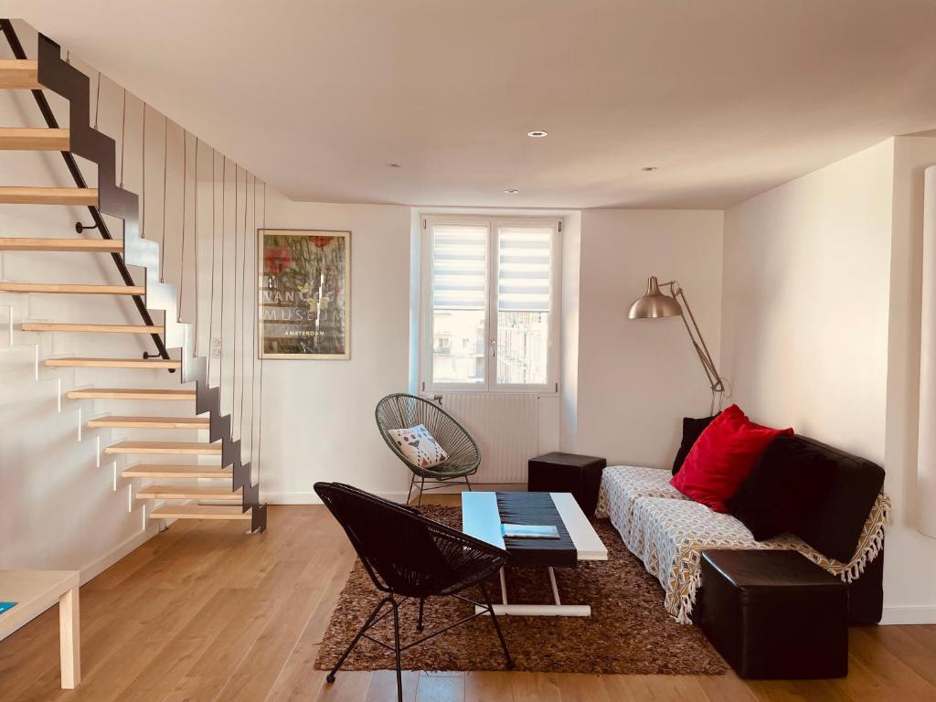 a living room with a couch and a staircase at **La Bretonnerie, bel appartement de standing in Concarneau