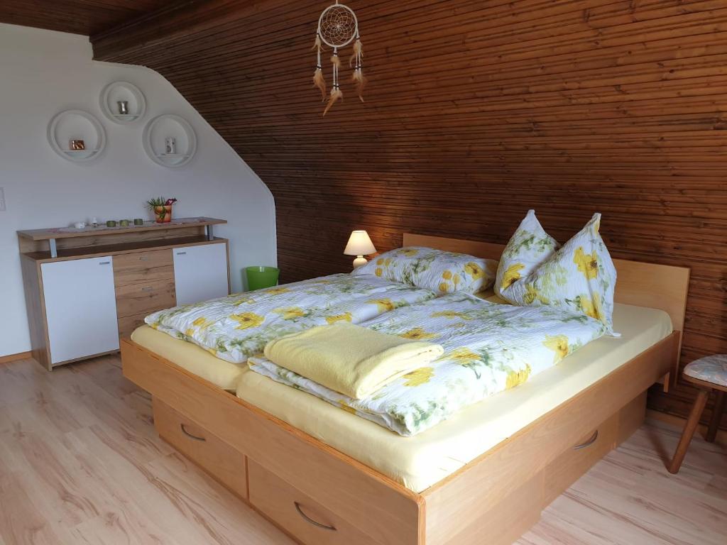 1 dormitorio con 1 cama grande y pared de madera en Ferienhaus Annemarie en Ludmannsdorf