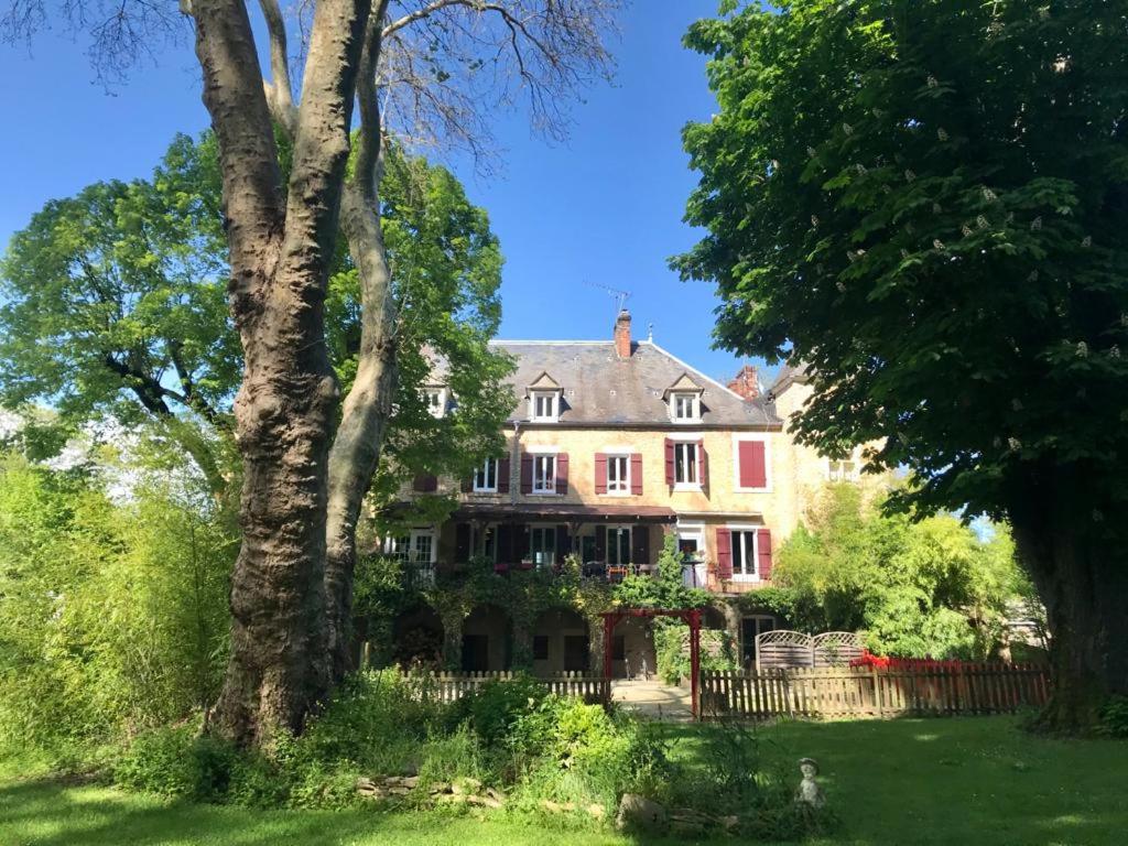 ein großes Haus in einem Hof mit Bäumen in der Unterkunft Maison Ichigo in Voutenay-sur-Cure