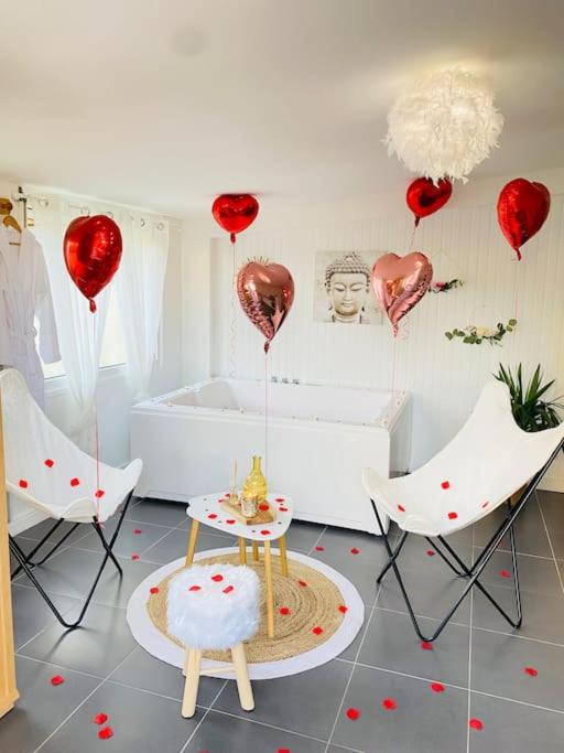 a room with red hearts and a tub and chairs at Maison vue sur mer in Bretteville