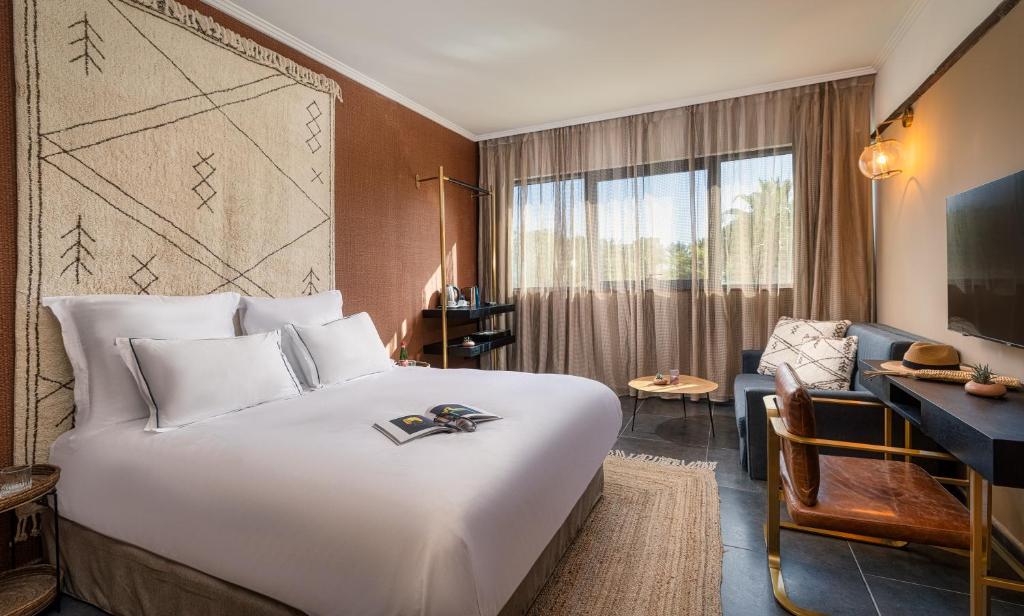 a hotel room with a large bed and a desk at Brown Red Sea - Central Park in Eilat