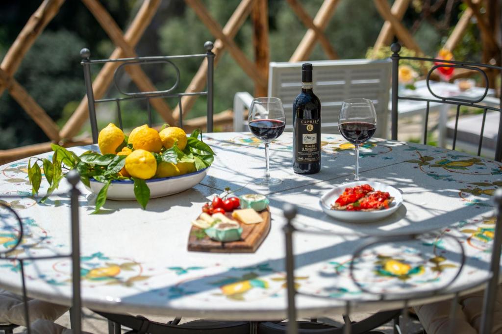 a table with two glasses of wine and a bowl of fruit at Villa Briganti Seaview Terrace in Positano