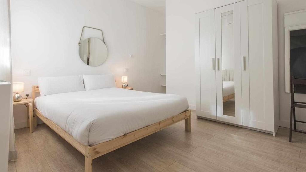 Habitación blanca con cama y espejo en Apartamentos Dimax by Toledo AP en Toledo
