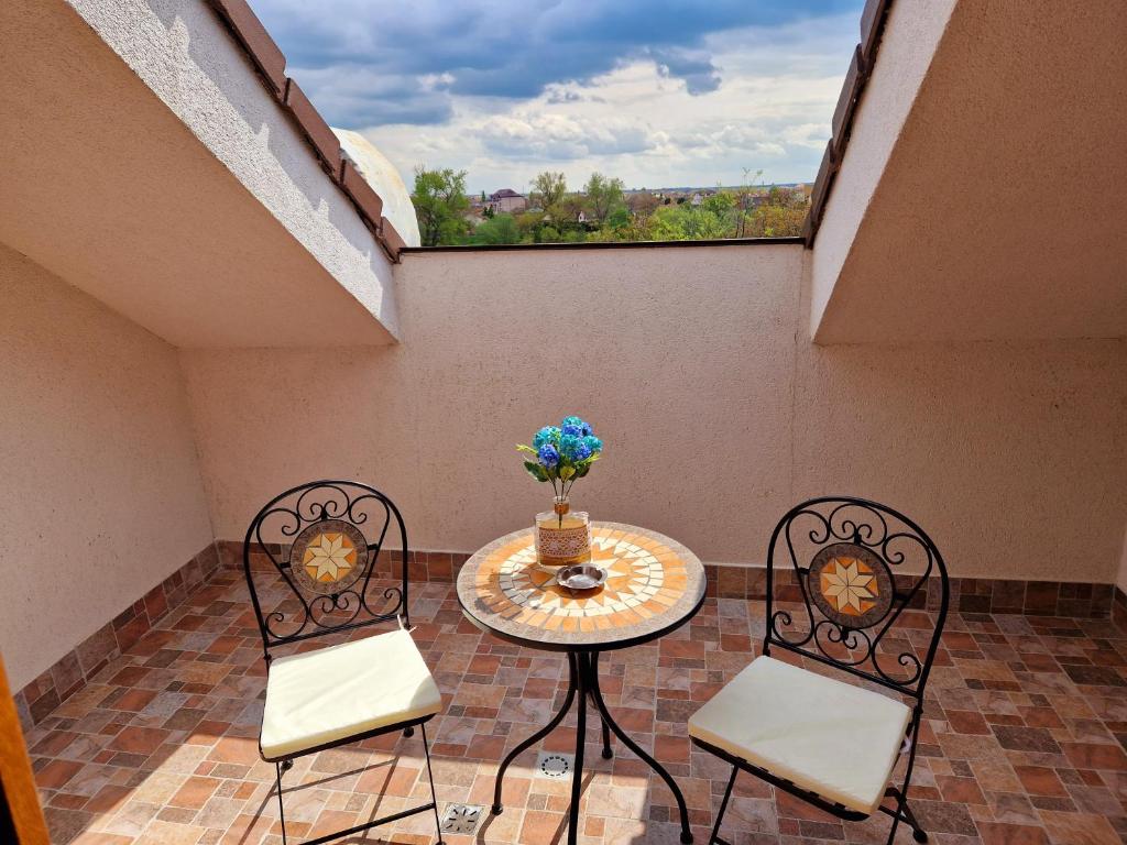 einen Balkon mit einem Tisch, 2 Stühlen und einem Fenster in der Unterkunft ORI Blue Studio Malul Muresului in Arad