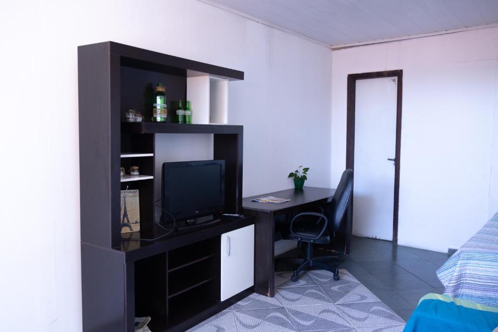 a room with a desk with a computer and a television at Apartamentos na região Central Cobertura e 2 quartos in Ponta Grossa
