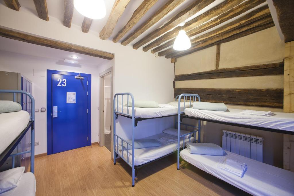 a room with three bunk beds and a blue door at El Albergue de la Catedral in Vitoria-Gasteiz
