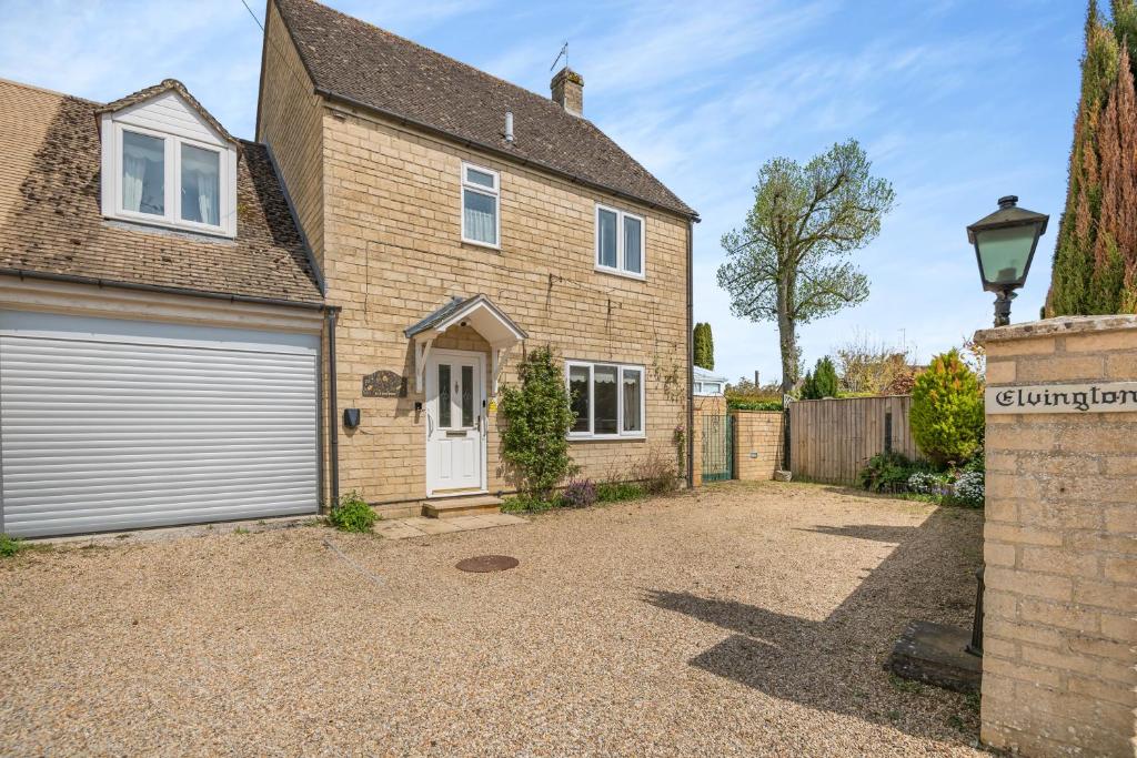a detached house with a garage and a driveway at Elvington Cottage - Family-friendly cheerful house at the heart of the Cotswolds in Bourton on the Water